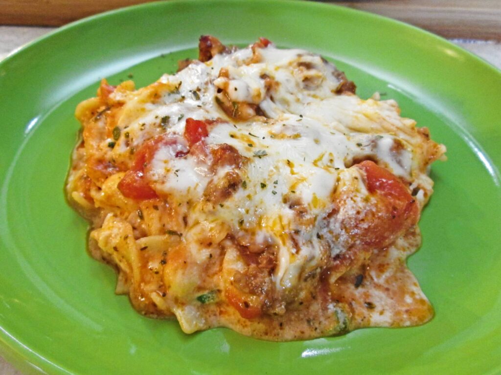 Close-up of a slice of egg noodle lasagna on a green plate.