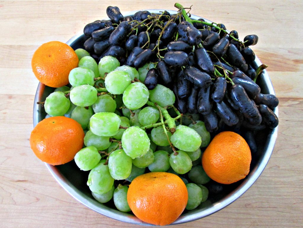 Fresh grapes and oranges prepared for homemade wine making in the primary fermentation stage.