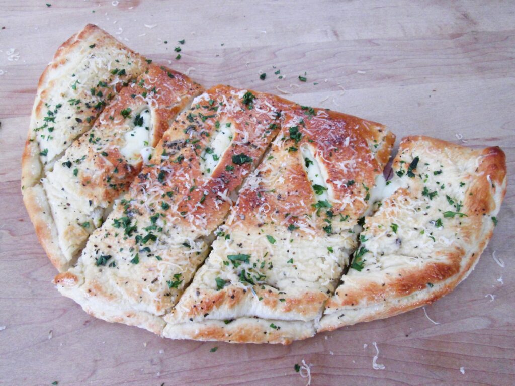 Sliced portions of a large calzone, showing melted cheese and ham.